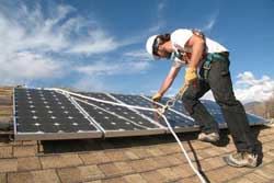 Worker installing solar panel on a roof.