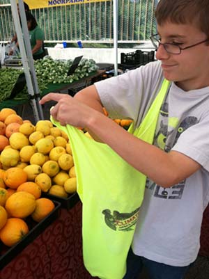 Boy uses his Climate Kids t-shirt bag at a farmer's market.