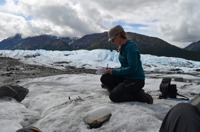 Photo of Kimberly Casey records information in her notebook while visiting Matanuska glacier in Alaska.