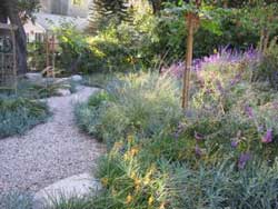 Same yard, with a curving gravel path through colorful, natural-looking plants.