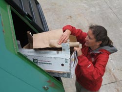 Kate puts a cardboard box in a recycling bin.