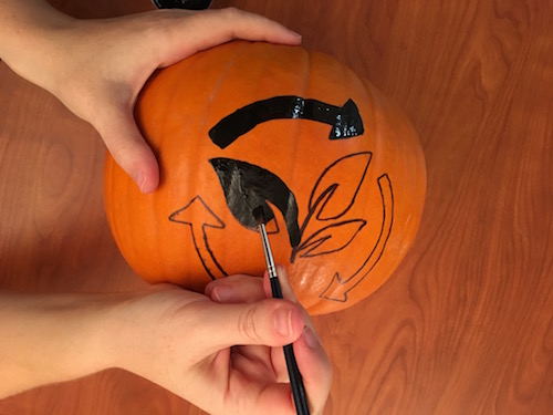 a paintbrush with black paint is being used to fill in the carbon cycle shape on a pumpkin