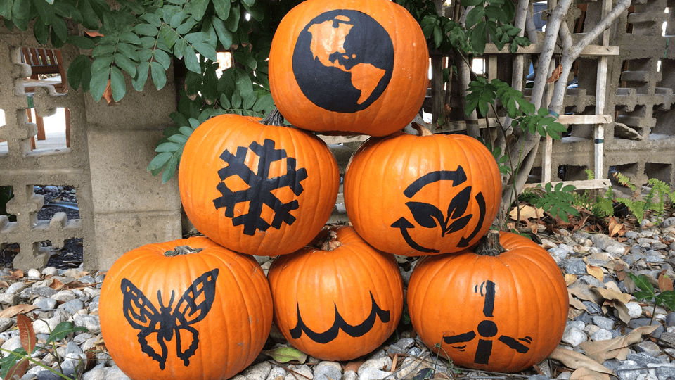 Image of a stack of pumpkins with various stencil designs painted on them.